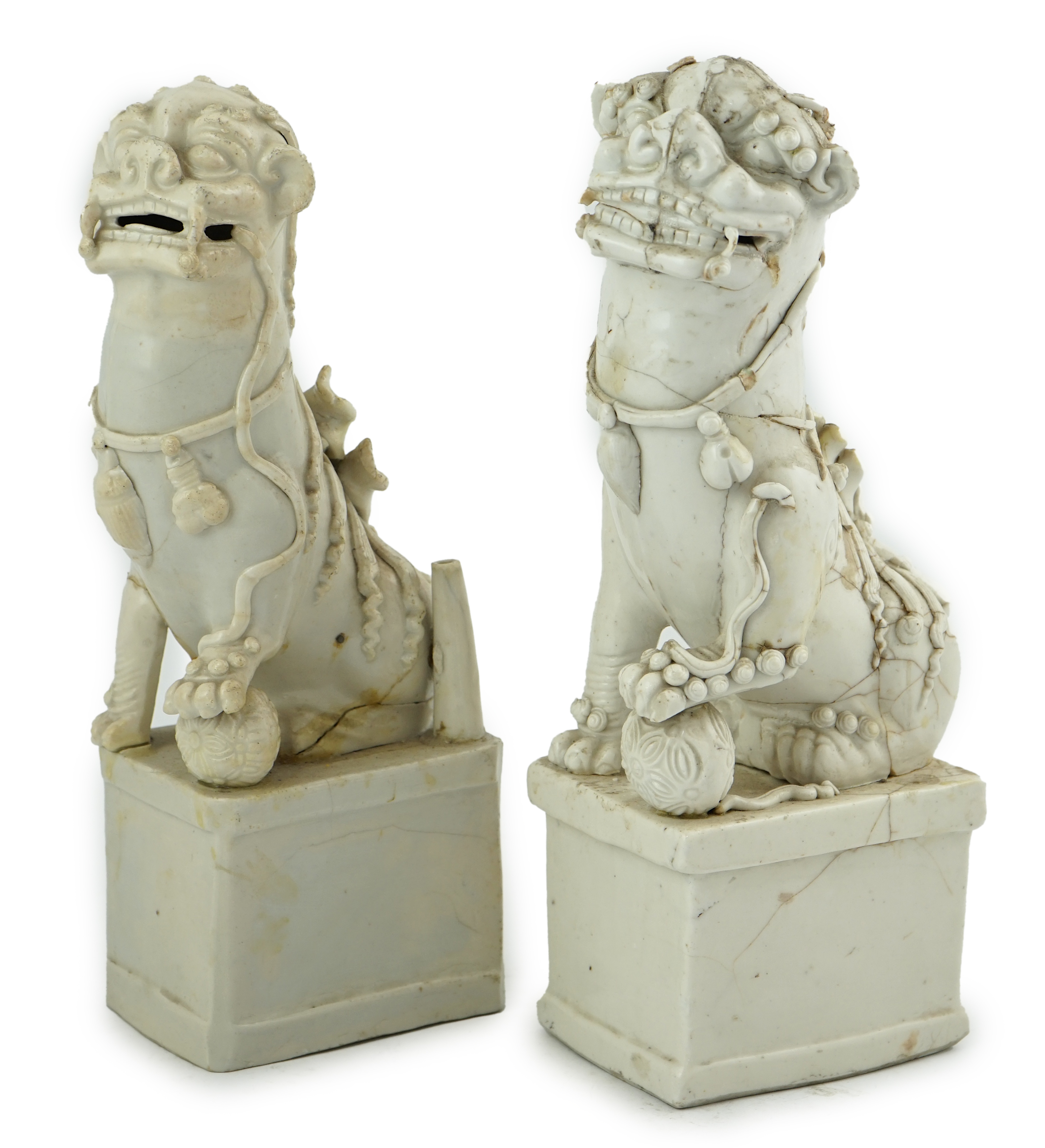 Two large Chinese Dehua blanc de chine Buddhist lion joss-stick holders, Kangxi period, each seated, one paw raised on a ball, on rectangular pedestal basis, 35cm high, Condition - extensive cracks or repairs